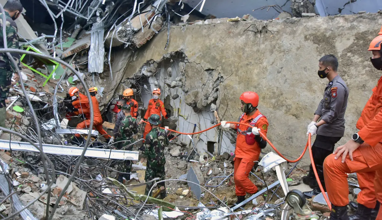 Tim penyelamat mencari korban di reruntuhan gedung pemerintah yang runtuh saat gempa bumi di Mamuju, Sulawesi Barat, Jumat (15/1/2021). Jaringan listrik di wilayah itu juga dilaporkan mengalami pemadaman. (AP Photo/Daus Thobelulu)