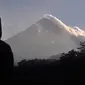 Seorang pria menyaksikan Gunung Merapi memuntahkan asap vulkanik di Yogyakarta, Indonesia, Selasa, (22/5). Pihak berwenang meningkatkan kewaspadaan terhadap Gunung Merapi yang bergejolak di pulau Jawa. (AP Photo/Slamet Riyadi)