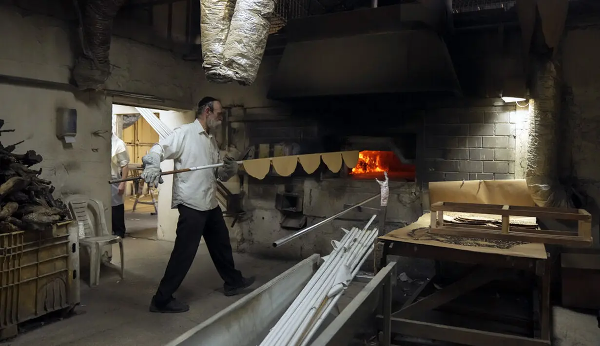 Yahudi Ultra-Ortodoks menyiapkan matzoh khusus di sebuah toko roti di Ashdod, Israel, 11 April 2022. Orang Yahudi dilarang makan makanan beragi selama liburan Paskah merayakan kisah alkitabiah tentang bangsa Israel saat melarikan diri dari perbudakan dan eksodus dari Mesir. (AP Photo/Tsafrir Abayov)