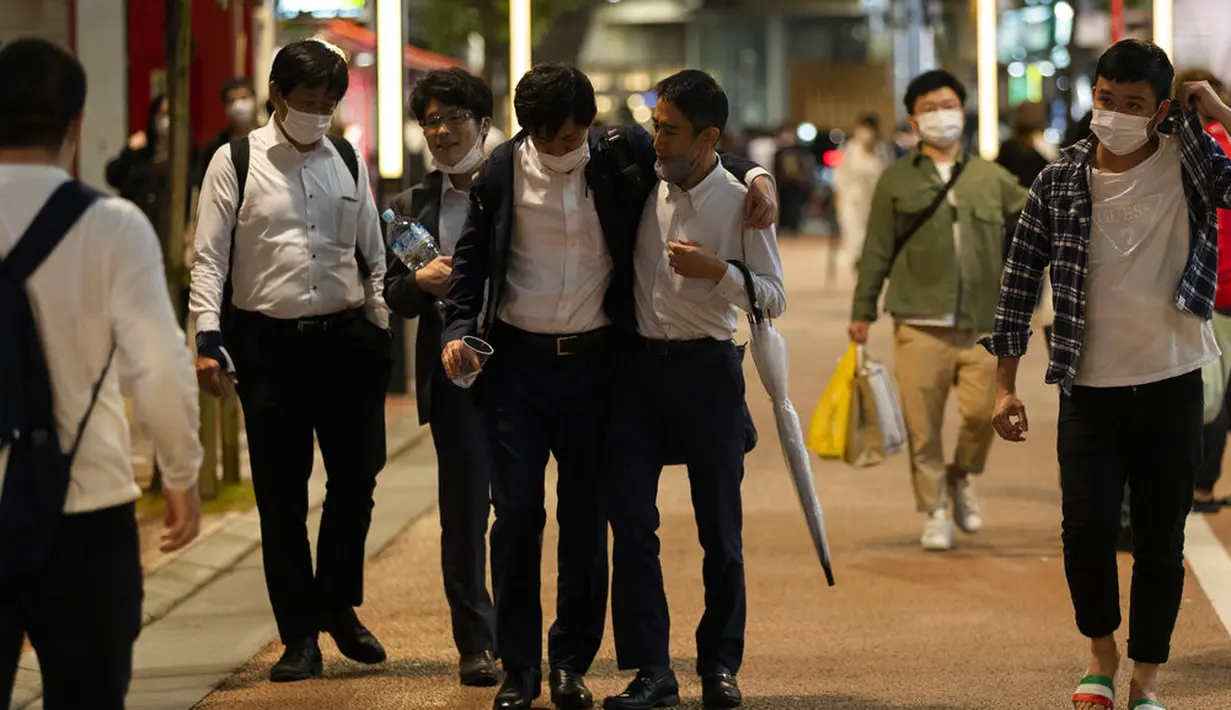 Orang-orang berjalan di jalan menuju stasiun kereta api pada malam pertama pencabutan status darurat virus corona oleh pemerintah di Tokyo, Jepang, Jumat (1/10/2021). (AP hoto/Hiro Komae)