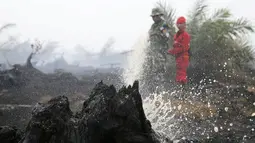 Seorang anggota TNI dan petugas pemadam berusaha memadamkan api di perkebunan kelapa sawit di Desa Padamaran, Ogan Komering Ilir , Sumatera Selatan, Sabtu (12/9/2015). Kebakaran lahan menyebabkan kabut asap di sejumlah wilayah. (REUTERS/Beawiharta)