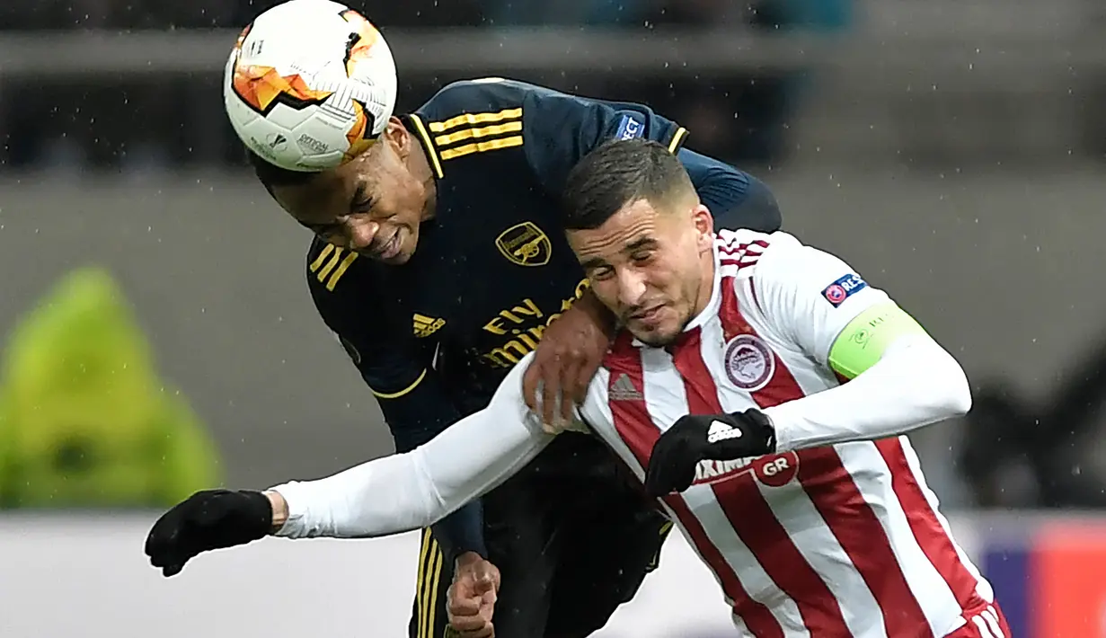Bek Olympiakos Piraeus, Omar Elabdellaoui (kanan) berebut bola dengan gelandang Arsenal, Joe Willock pada leg pertama babak 32 besar Liga Europa di Georgios Karaiskakis Stadium, Kamis (20/2/2020). Arsenal susah payah menaklukkan Olympiakos Piraeus 1-0. (LOUISA GOULIAMAKI / AFP)