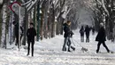 Orang-orang berjalan-jalan atau berlari di sepanjang gang yang tertutup salju di Taman Prater di Wina, Austria pada 3 Desember 2023. (Alex HALADA / AFP)