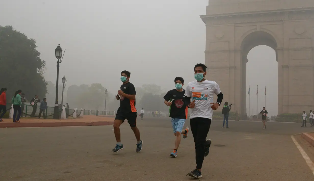 Sejumlah peserta yang mengikuti lomba New Delhi 10K berlari di depan India Gate yang diselimuti kabut tebal di New Delhi, India (31/10). Kabut asap ini diklaim sebagai kabut asap terparah yang dialami oleh New Delhi dalam 17 tahun. (AFP/Dominique Faget)