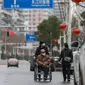 Warga mengenakan masker berjalan di sebuah jalan di Wuhan di provinsi Hubei tengah China (3/3/2020). Sejauh ini, total 80.026 kasus virus corona terkonfirmasi di wilayah China daratan. (AFP/STR)