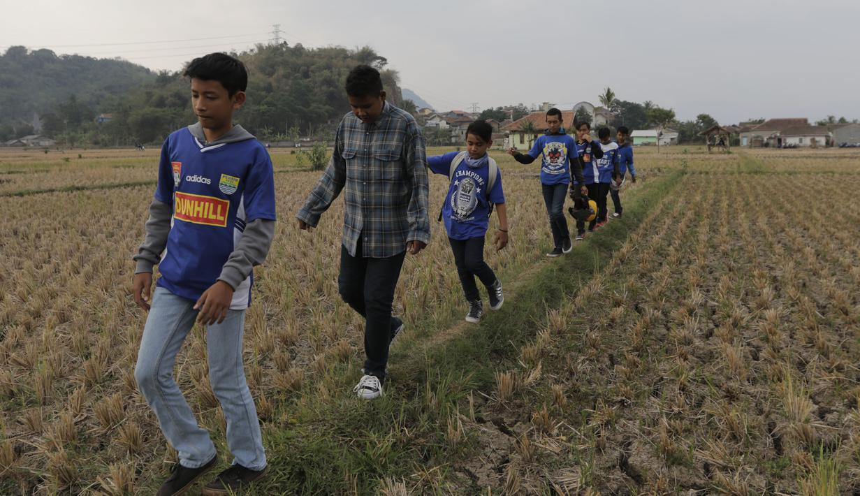 Penuh semangat para Bobotoh melintasi sawah menuju Stadion Si Jalak Harupat, Bandung. (Bola.com/Vitalis Yogi Trisna)