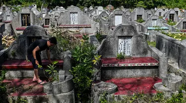 Warga keturunan Tionghoa membersihkan makam keluarga saat Festival Cheng Beng di Pemakaman Tionghoa di Japakeh, Banda Aceh, Aceh, Minggu (26/3/2023). (CHAIDEER MAHYUDDIN/AFP)