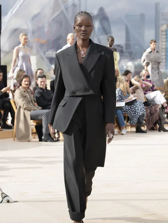 aket double-breasted trompe l'oeil asimetris dipadu dengan high-waisted peg trousers, yang dirancang dalam bahan wol berwarna hitam. Foto: Document/Alexander McQueen.