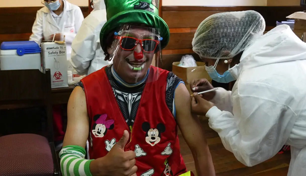 Seorang badut disuntik vaksin COVID-19 Sinopharm selama kampanye vaksinasi yang menargetkan usia antara 18 dan 30 tahun di Universitas Negeri San Andres di La Paz, Bolivia, Senin (5/7/2021). Presiden Luis Arce menjanjikan upaya vaksinasi "besar-besaran" pada Juli dan Agustus. (AP Photo/Juan Karita)