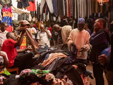 Pembeli memilih barang dari tumpukan pakaian bekas yang dijual di pasar di Kampala pada 7 Oktober 2023. (BADRU KATUMBA / AFP)