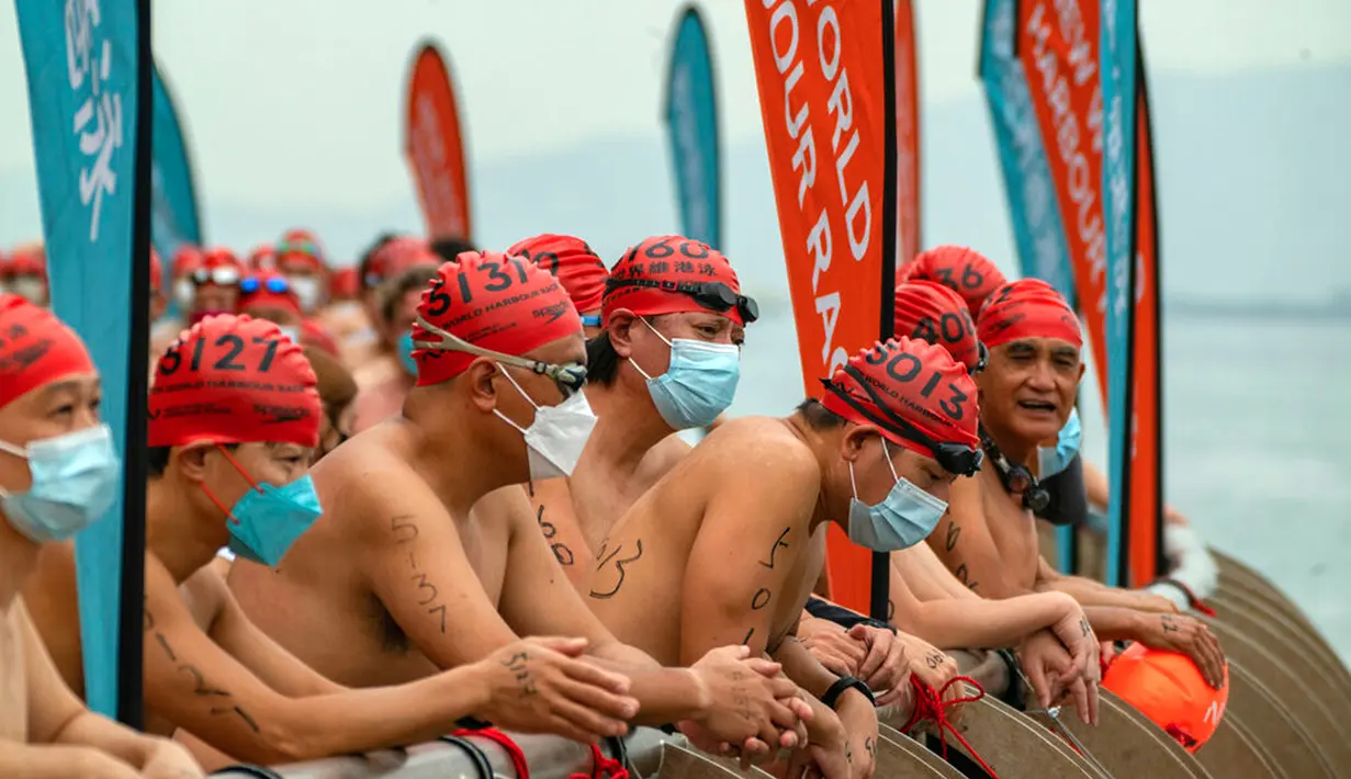 Para perenang menunggu di garis start jelang lomba renang tahunan di Pelabuhan Victoria, Hong Kong, Minggu (23/10/2022). Lomba ini adalah salah satu dari sedikit acara olahraga besar yang mendapatkan izin untuk dilanjutkan tahun ini. (AP Photo/Anthony Kwan)