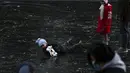 Seorang anak jatuh saat bermain di sungai beku dekat pemukiman warga, Beijing, China, 3 Januari 2022. Libur Tahun Baru dimanfaatkan warga untuk bermain ice skating di sungai dan danau yang membeku. (AP Photo/Andy Wong)