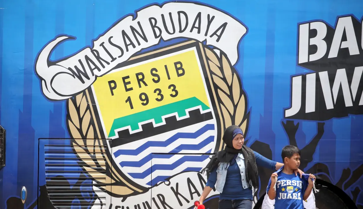 Pendukung Persib berjalan di samping Bus Bandung Tour on Bus (Bandros) yang akan mengangkut para pemain Persib Bandung dalam Pawai Persib Juara Piala Presiden di Kota Baru Parahyangan, Bandung, Minggu (25/10/2015). (Bola.com/Nick Hanoatubun)