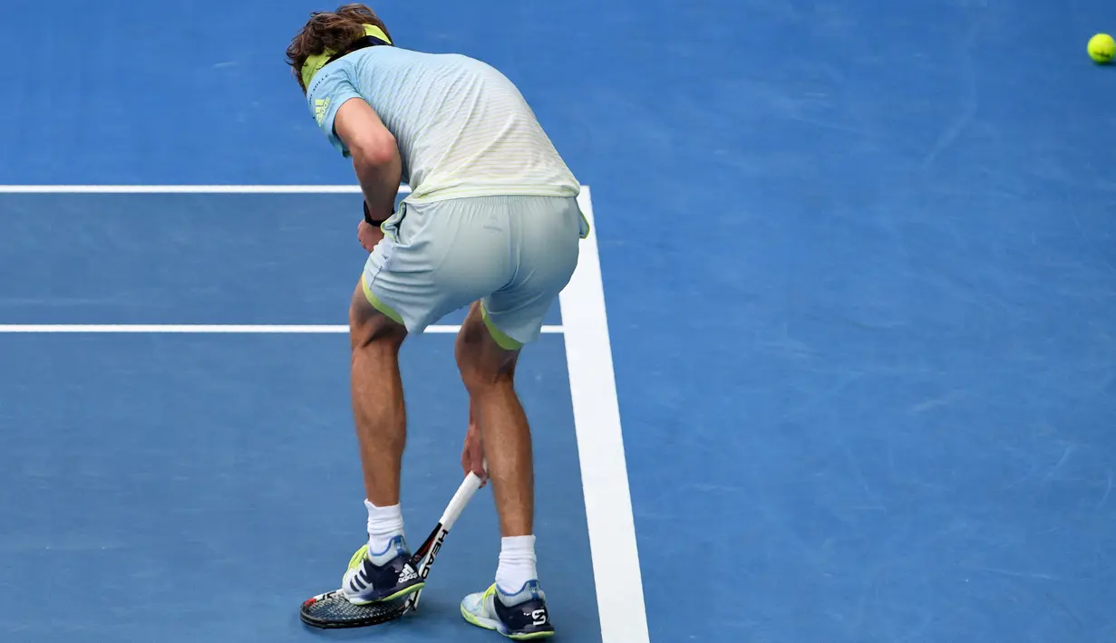 Petenis Jerman, Alexander Zverev menginjak raketnya seusai menghadapi petenis Korea Selatan, Chung Hyeon di turnamen Australia Terbuka, 20 Januari 2018.  Kalah bermain, Zverev kesal dan membanting raketnya hingga rusak. (SAEED KHAN/AFP)