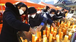 Para orangtua meletakkan lilin selama kebaktian khusus untuk mendoakan keberhasilan anak-anak mereka dalam ujian masuk perguruan tinggi di Kuil Buddha Jogyesa, Seoul, Korea Selatan, Kamis (3/12/2020). Ujian diikuti ratusan ribu siswa, termasuk puluhan siswa pasien COVID-19. (AP Photo/Ahn Young-joon)
