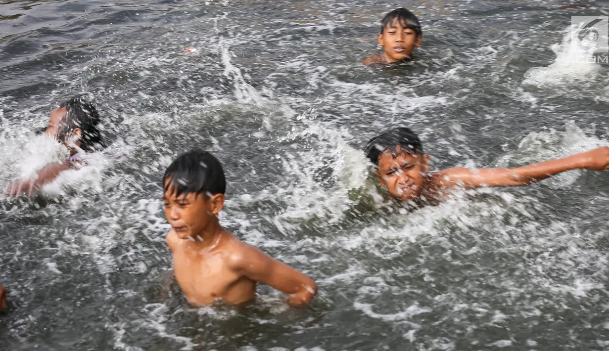 Anak-anak berenang di Kanal Banjir Barat (KBB) yang hitam di Petamburan, Jakarta, Senin (12/8/2019). Anak-anak memanfaatkan waktu pulang sekolah mereka untuk berenang dan mencari ikan di KBB saat musim kemarau. (Liputan6.com/Fery Pradolo)