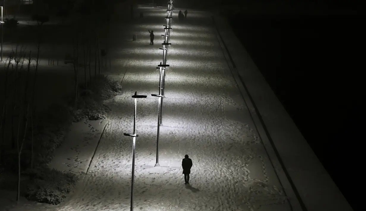Pejalan kaki berjalan di sepanjang promenade yang tertutup salju saat salju turun di Istanbul, Turki, Sabtu (12/3/2022). Salju tebal menutupi Istanbul dan mengganggu lalu lintas udara menyebabkan transportasi laut serta darat terhenti, hingga memaksa penutupan sekolah. (AP Photo/Emrah Gurel)