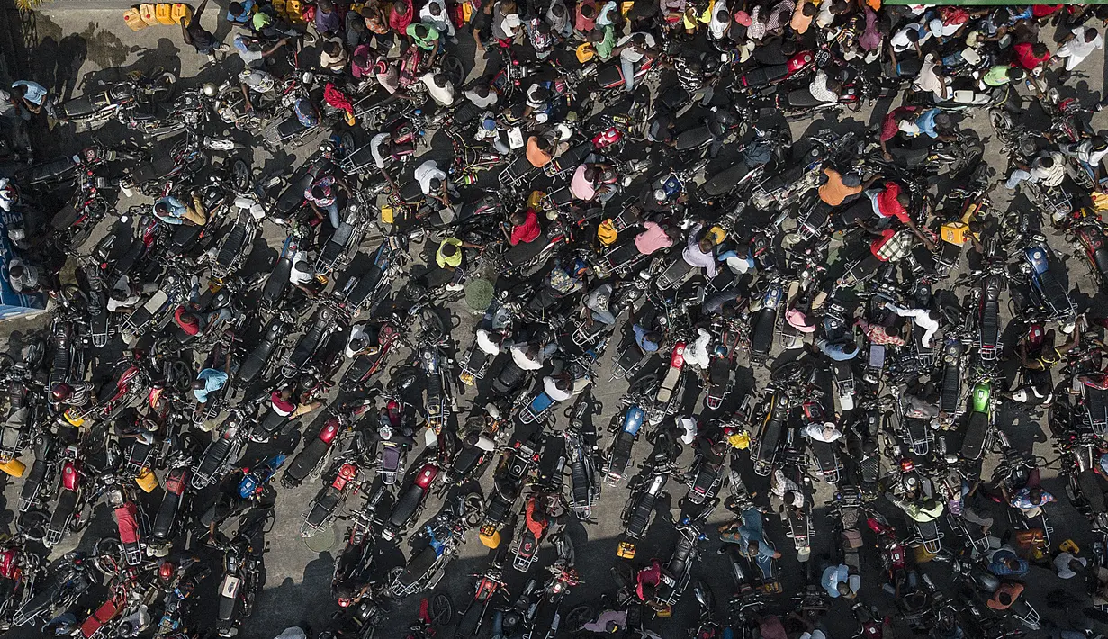 Orang-orang berkerumun di sebuah pompa bensin dengan harapan mengisi sepeda motor mereka selama kekurangan bahan bakar nasional di Port-au-Prince, Haiti, Minggu (31/10/2021). Seperti diketahui, krisis BBM tengah melanda kawasan Haiti sejak beberapa hari belakangan. (AP Photo/Matias Delacroix)