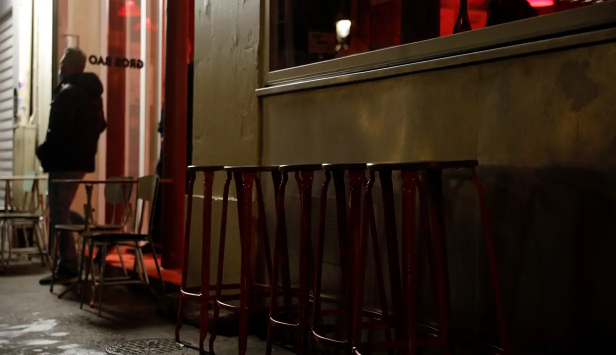 Seorang pria berdiri dekat kursi kosong di luar bar yang tutup di Paris pada Senin (5/10/2020). Bar dan kafe di Paris serta pinggiran kota terdekatnya ditutup mulai 6 Oktober selama dua minggu karena ibu kota Prancis ditempatkan pada kewaspadaan maksimum  Covid-19. (GEOFFROY VAN DER HASSELT/ AFP)