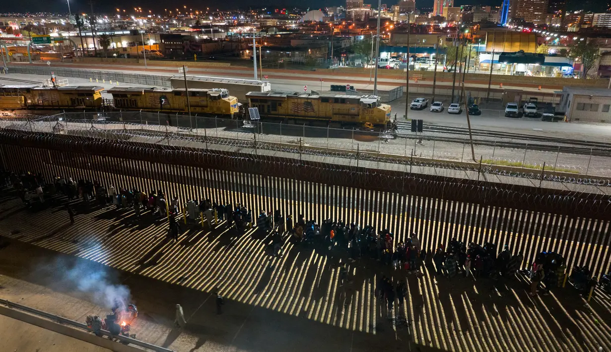 Migran bermalam di luar pagar perbatasan AS-Meksiko sambil menunggu pengajuan suaka di El Paso, Texas, di Ciudad Juarez, Meksiko, Rabu (21/12/2022). Pihak Presiden Joe Biden telah meminta pengadilan untuk mencabut pembatasan, tetapi pengadilan menolak melakukan itu sebelum Natal berakhir. (JOHN MOORE / GETTY IMAGES NORTH AMERICA / Getty Images via AFP)