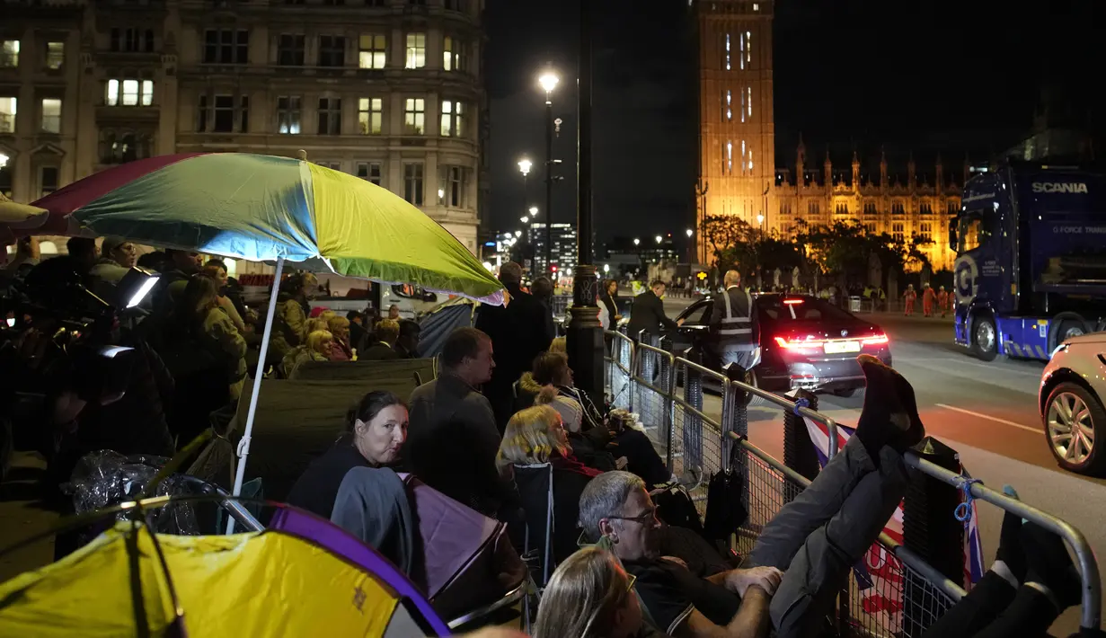 Orang-orang berkemah di depan Istana Westminster pada malam pemakaman Ratu Elizabeth II di London, Minggu, 18 September 2022. Pemakaman Ratu Elizabeth II, raja terlama di Inggris, berlangsung pada Senin (19/9). (AP/Christophe Ena)