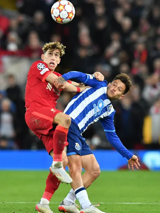 Bek Liverpool Kostas Tsimikas bersaing dengan gelandang FC Porto Otavio pada pertandingan kelima Grup B Liga Champions di Anfield, Kamis (25/11/2021) dini hari WIB. Kemenangan Liverpool 2-0 atas sang tamu FC Porto dipersembahkan oleh gol Thiago Alcantara dan Mohamed Salah. (Anthony Devlin/AFP)