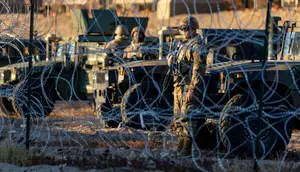 Tentara Pengawal Nasional Texas berjaga di belakang kawat berduri di perbatasan AS-Meksiko, Ciudad Juarez, Meksiko, Rabu (21/12/2022). Kebijakan Judul 42 ini dilakukan Trump untuk menghentikan penyebaran virus Corona dan memungkinkan AS mengusir hampir semua orang yang tertangkap melewati perbatasan secara ilegal. (JOHN MOORE / GETTY IMAGES NORTH AMERICA / Getty Images via AFP)