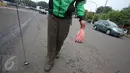 Pengendara Gojek bernama Ari mencari ranjau paku yang berserakan di sekitar Istana Negara, Jakarta, Minggu (14/8). Meskipun tak dibayar, Ari berinisiatif untuk mengumpulkan ranjau paku yang merugikan pengendara tersebut. (Liputan6.com/Immanuel Antonius)