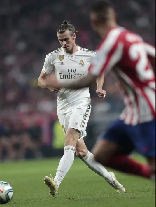 Penyerang Real Madrid, Gareth Bale mengumpan bola saat bertanding melawan Atletico Madrid pada pertandingan lanjutan La Liga di stadion Wanda Metropolitano, Spanyol (28/9/2019). Madrid dan Atletico bermain imbang 0-0. (AP Photo/Bernat Armangue)
