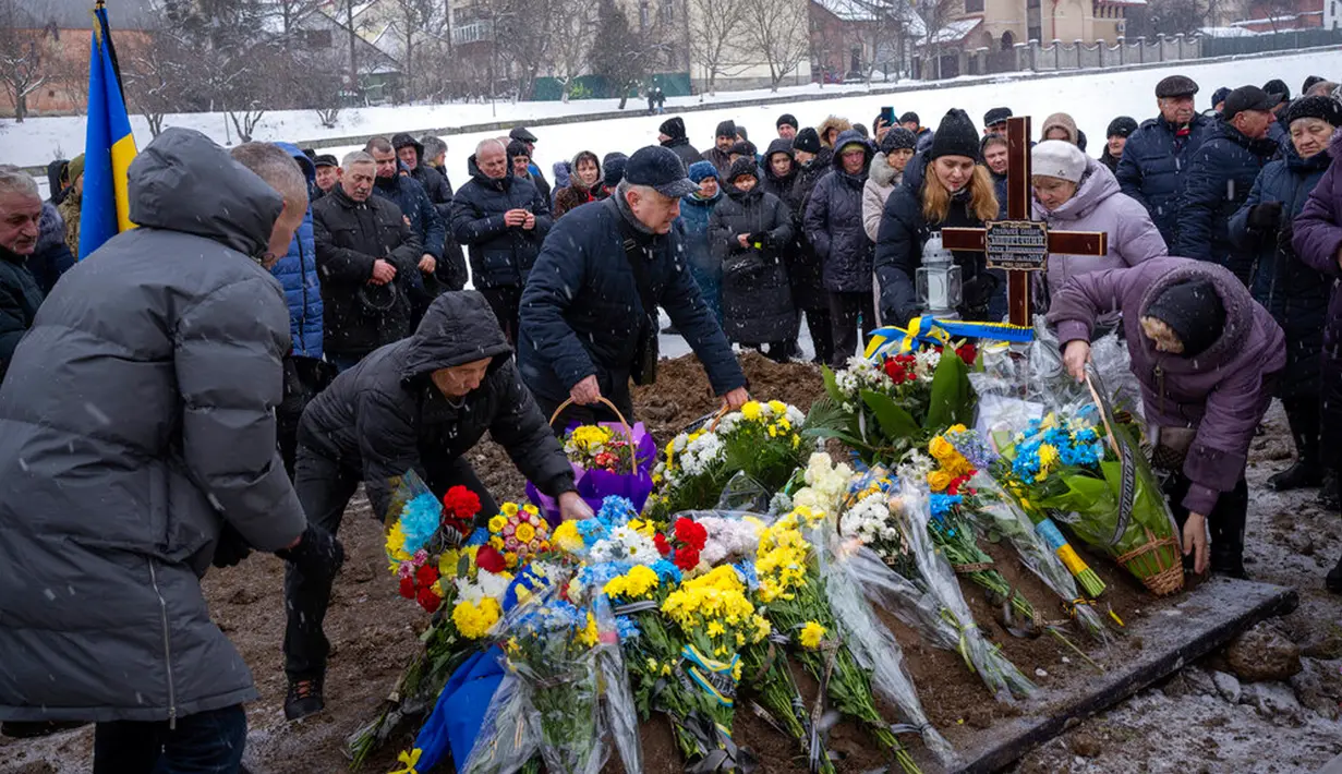 Kerabat menempatkan bunga pada makam Yevhen Zapotichnyi, seorang prajurit militer Ukraina yang terbunuh di timur negara itu, saat pemakamannya di Lviv, Ukraina, 7 Februari 2023. Memasuki hari ke-350 invasi Rusia ke Ukraina, korban jiwa terus berjatuhan di antara kedua belah pihak yang berseteru. (AP Photo/Emilio Morenatti)