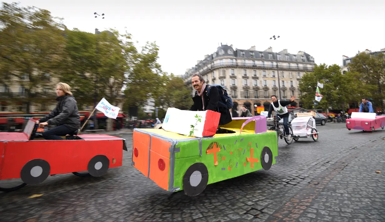 Sejumlah orang naik sepeda yang dihias kardus berbentuk mobil di Place de la Bastille, Paris, Prancis (1/10). Pemerintah Prancis mendorong warganya untuk mengurangi penggunaan kendaraan bermotor guna mengurangi polusi. (AFP Photo/Eric Feferberg)
