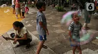 Anak-anak bermain gelembung sabun saat menghabiskan waktu di Taman Puring, Jakarta, Minggu (9/1/2022). Di tengah ancaman penyebaran covid-19 varian Omicron dan pemberlakukan PPKM level 2, masyarakat tetap melakukan aktivitas pada akhir pekan di luar rumah. (Liputan6.com/Johan Tallo)