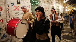 Kelompok pemuda Palestina memukul gendang ketika membangunkan kaum muslim untuk sahur di Kota Tua Yerusalem, Selasa (5/6). Dalam tradisi Musaharati ini, biasanya mereka memakai alat musik sambil menyanyikan lagu-lagu religius. (AP/Mahmoud Illean)