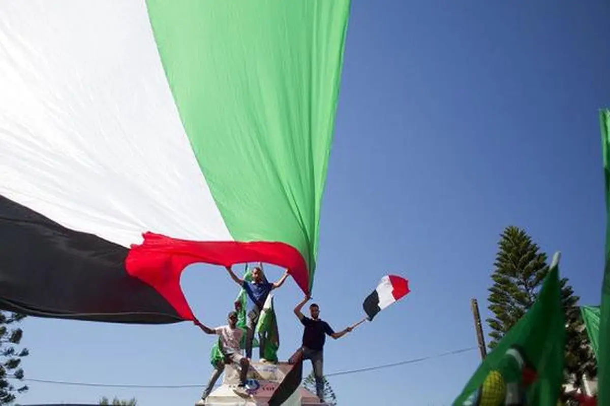 Warga Palestina membentang bendera negara mereka, bergembira menyambut rekonsiliasi antara Hamas dan Fatah