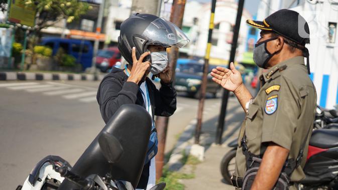 Petugas melakukan sosialisasi penggunaan masker kepada pengendara sepeda motor di kawasan Depok, Jawa Barat, Senin (20/7/2020). Warga yang tidak mengenakan masker nantinya akan dikenai denda Rp 50 ribu atau sanksi sosial sesuai Perwali Nomor 45 tahun 2020. (Liputan6.com/Immanuel Antonius)