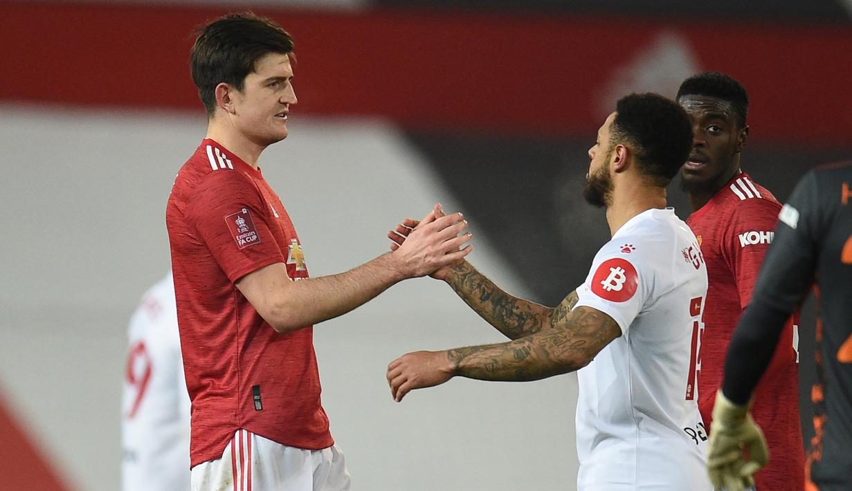 Bek Manchester United, Harry Maguire (kiri) berjabat tangan dengan striker Watford, Andre Gray usai berakhirnya laga babak ke-3 Piala FA 2020/21 di Old Trafford, Sabtu (9/1/2021). Manchester United menang 1-0 atas Watford. (AFP/Oli Scarff/Pool)