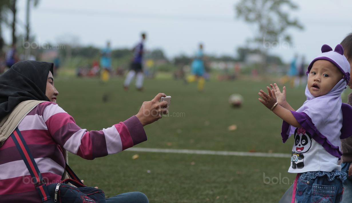 Seorang ibu dan anaknya berfoto saat menonton  Bhayangkara FC melawan Persita pada laga uji coba di Lapangan NYTC Sawangan, Depok, (11/01/2018). Bhayangkara FC kalah 0-2. (Bola.com/Nicklas Hanoatubun)