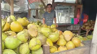 Suhe ‘Kelapa Muda’, salah satu pedagang kelapa muda di bilangan Alun-alun Tarogong, Garut, terlihat tengah menjajakan barang dagangnnya menjelang iftor Ramadan, Selasa (5/4/2022). (Liputan6.com/Jayadi Supriadin)