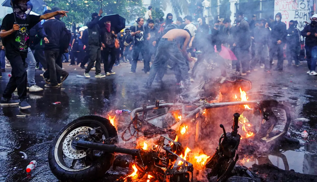 Para pengunjuk rasa membakar sepeda motor dalam sebuah demonstrasi menentang revisi Undang-Undang Tentara Nasional Indonesia (UU TNI) di depan Kompleks Parlemen di Jakarta pada 27 Maret 2025. (AZWAR IPANK/AFP)