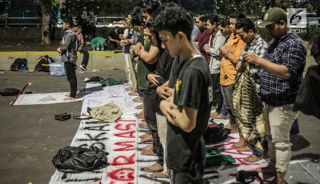 Massa dari Badan Eksekutif Mahasiswa Seluruh Indonesia (BEM SI) melakukan salat magrib disela unjuk rasa di depan gedung DPR/MPR RI, Jakarta, Selasa (1/10/2019). Di sela-sela agenda pelantikan anggota baru DPR RI 2019-2024, gelombang mahasiswa kembali menggelar demo. (Liputan6.com/Faizal Fanani)