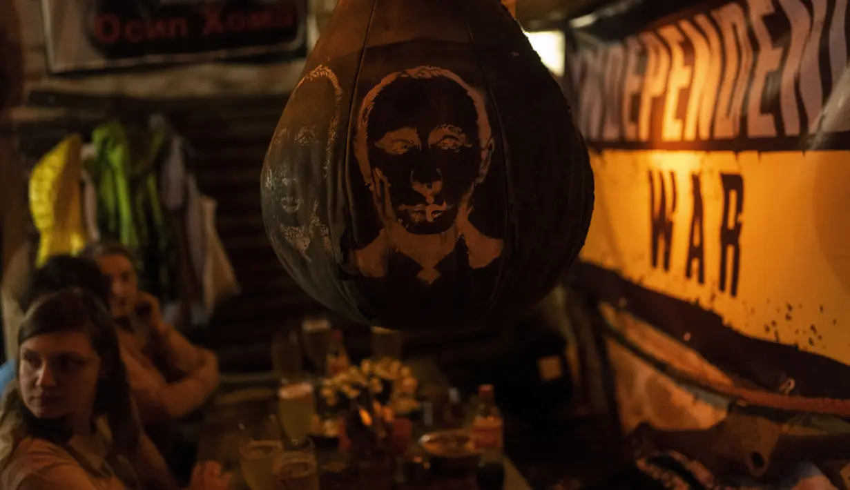 Tas tinju bergambar wajah Presiden Rusia Vladimir Putin tergantung di dalam bar di pusat kota Lviv, Ukraina barat, Selasa, 22 Maret 2022. Perang Rusia yang tak henti-hentinya di Ukraina memaksa lebih banyak pengungsi untuk meninggalkan rumah mereka. (AP Photo/Bernat Armangue)