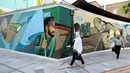 Pejalan kaki melewati lukisan mural yang menggambarkan para prajurit Iran di Palestine Square, Ibu Kota Teheran, Iran, Sabtu (22/6/2019). (ATTA KENARE/AFP)