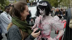 Seorang wanita mengenakan gaun berinteraksi dengan pengunjung saat "Zombie Walk" di Paris, Prancis (7/10). Dalam festival ini peserta berdandan dan mengenakan kostum layaknya zombie. (AFP Photo/Thomas Samson)