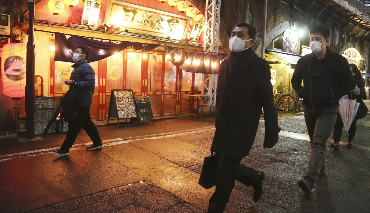 Orang-orang yang mengenakan masker untuk membantu melindungi diri dari penyebaran virus corona berjalan di sepanjang jalan yang dipenuhi bar dan restoran di Tokyo, Selasa (22/3/2022). Langkah-langkah pra-darurat untuk mencegah wabah Covid-19 telah dicabut. (AP Photo/Koji Sasahara)