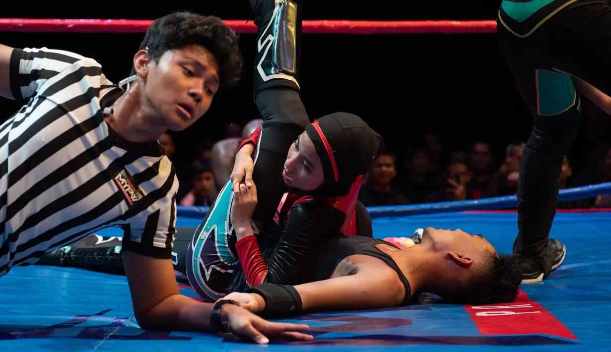 Pegulat hijab Malaysia, Nor "Phoenix" Diana melawan pegulat pria pada pertandingan yang diselenggarakan Malaysia Pro Wrestling di  Kuala Lumpur, 6 Juli 2019. Nor Diana berhasil menjadi juara wanita pertama, dengan titel Wrestlecon Champion, yang sebelumnya diraih oleh pegulat pria. (Mohd RASFAN/AFP)