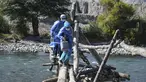 Petugas kesehatan menyeberangi Sungai Camana untuk vaksinasi Covid-19 kepada warga lanjut usia di desa pedalaman di Arequipa, Peru (2/7/2021). Peru menggencarkan vaksinasi warga lanjut usia dengan vaksin Pfizer-BioNTech sebagai upaya untuk mengatasi pencegahan pandemi Covid-19. (AFP/Diego Ramos)