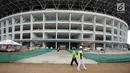 Pekerja melintas di area renovasi Stadion Utama GBK, Jakarta, Selasa (3/10). Sejumlah pembangunan Infastruktur Asian Games dipastikan akan selesai sesuai dengan target pemerintah, yaitu akhir tahun 2017. (Liputan6.com/Helmi Fithriansyah)