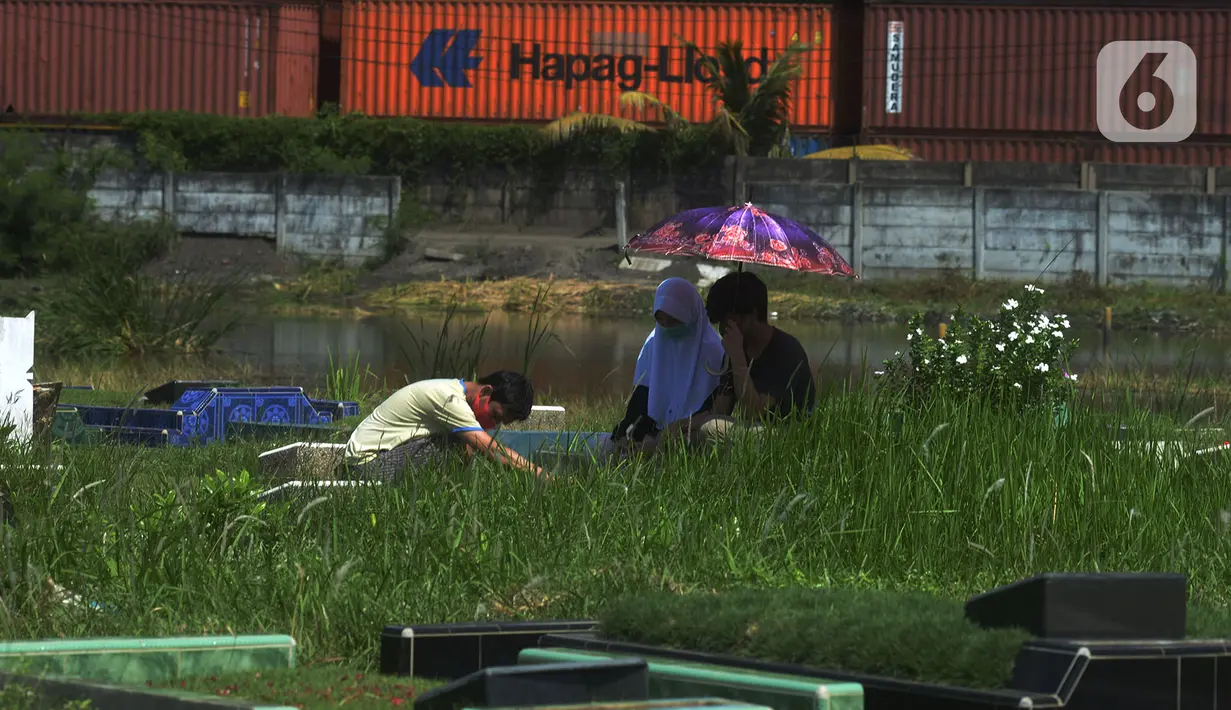 Warga berdoa saat ziarah kubur pada hari kedua Idul Fitri 1441 Hijriah di Tempat Pemakaman Umum (TPU) Semper, Jakarta, Senin (25/5/2020). Di tengah pandemi Covid-19,  peziarah kubur di TPU Semper berkurang. (merdeka.com/Imam Buhori)