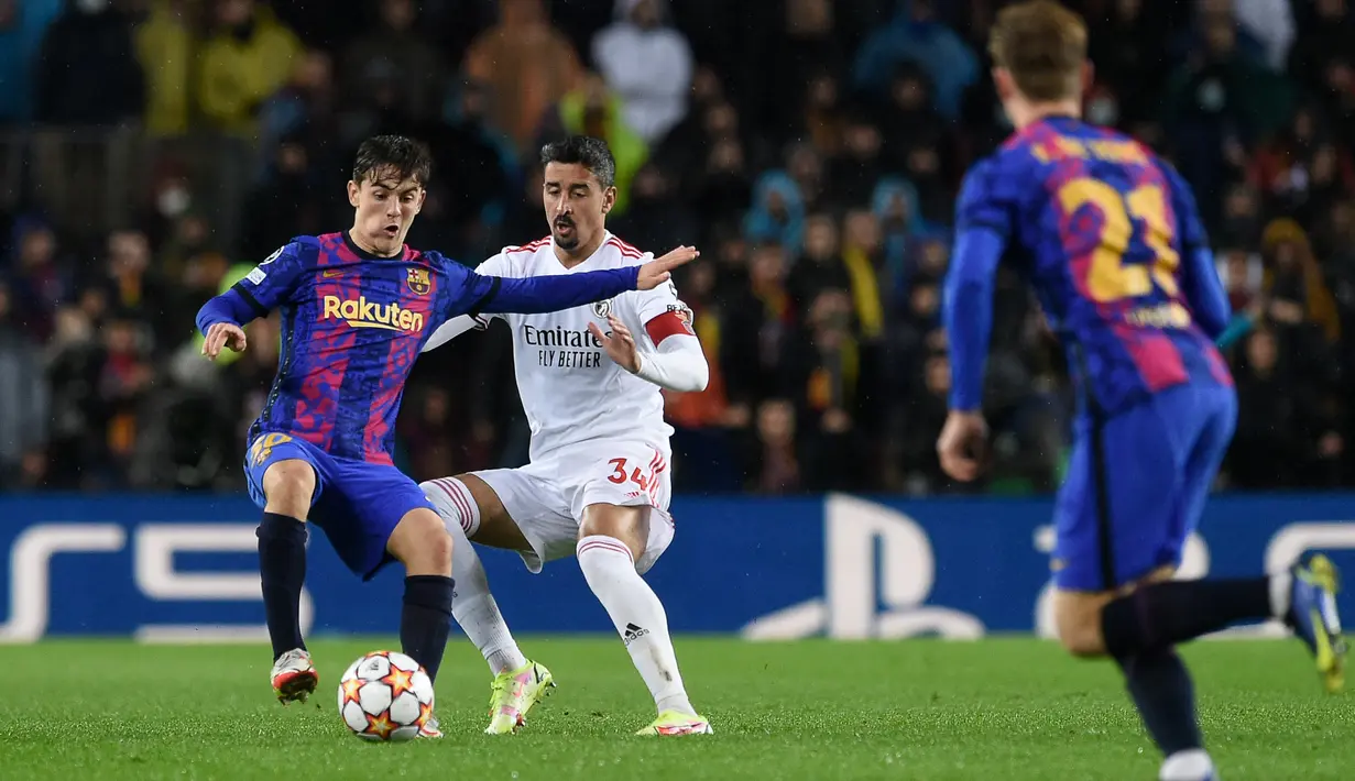 Gelandang Barcelona Gavi (kiri) berebut bola dengan bek Benfica Andre Almeida pada matchday kelima Grup E Liga Champions di Camp Nou, Rabu (24/11/2021) dini hari WIB. Barcelona hanya mampu bermain imbang 0-0 kala menjamu Benfica. (Josep LAGO / AFP)