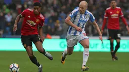 Striker Manchester United, Marcus Rashford berusaha membawa bola melewati gelandang Huddersfield, Aaron Mooy saat pertandingan Liga Inggris di stadion John Smith di Huddersfield (21/10). (AFP Photo/Lindsey Parnaby)
